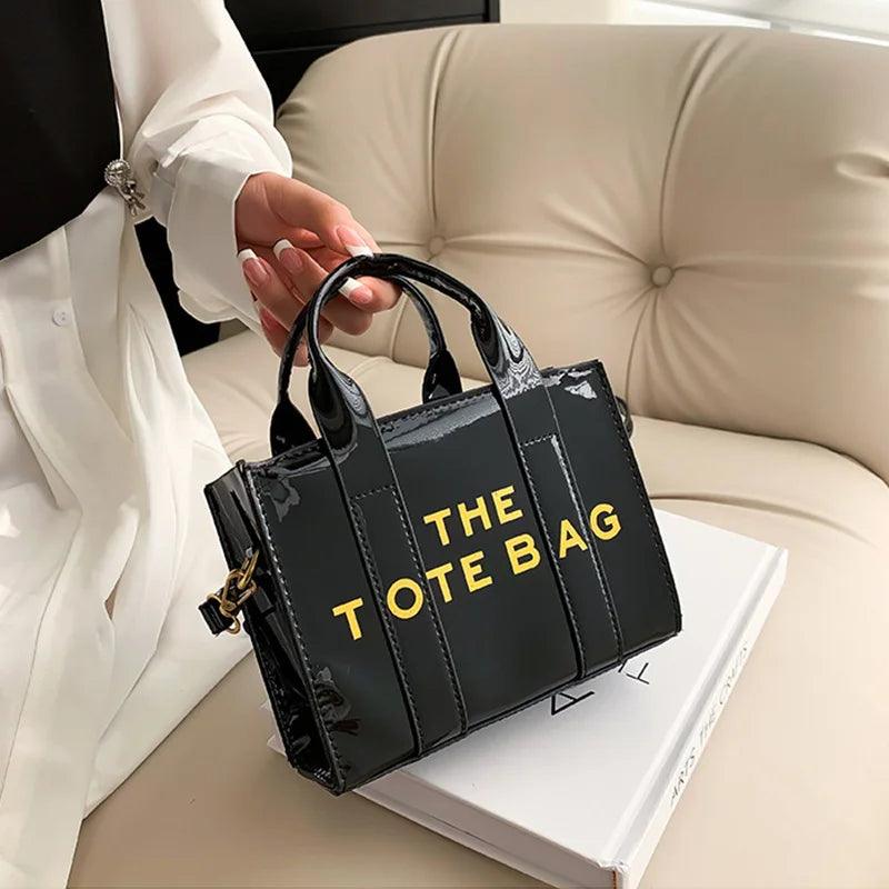 Black mini leather crossbody bag with gold lettering, top handles and crossbody strap