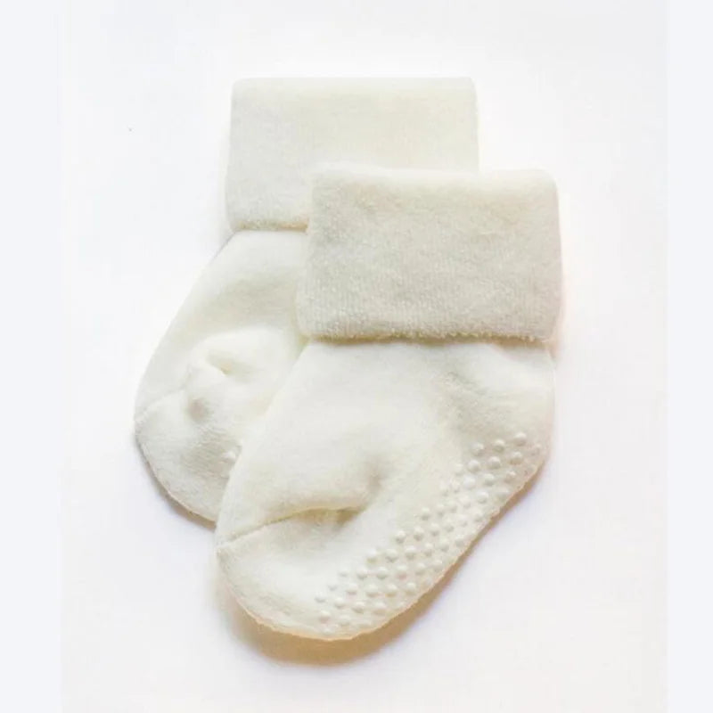White thick baby socks with white grippy dots on the sole