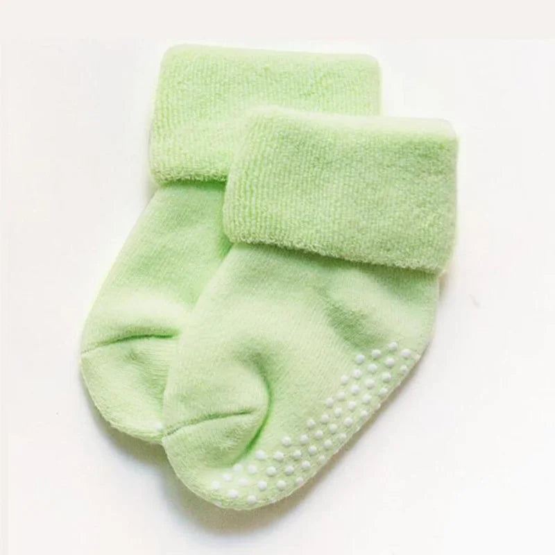 Light green thick baby socks with white grippy dots on the sole