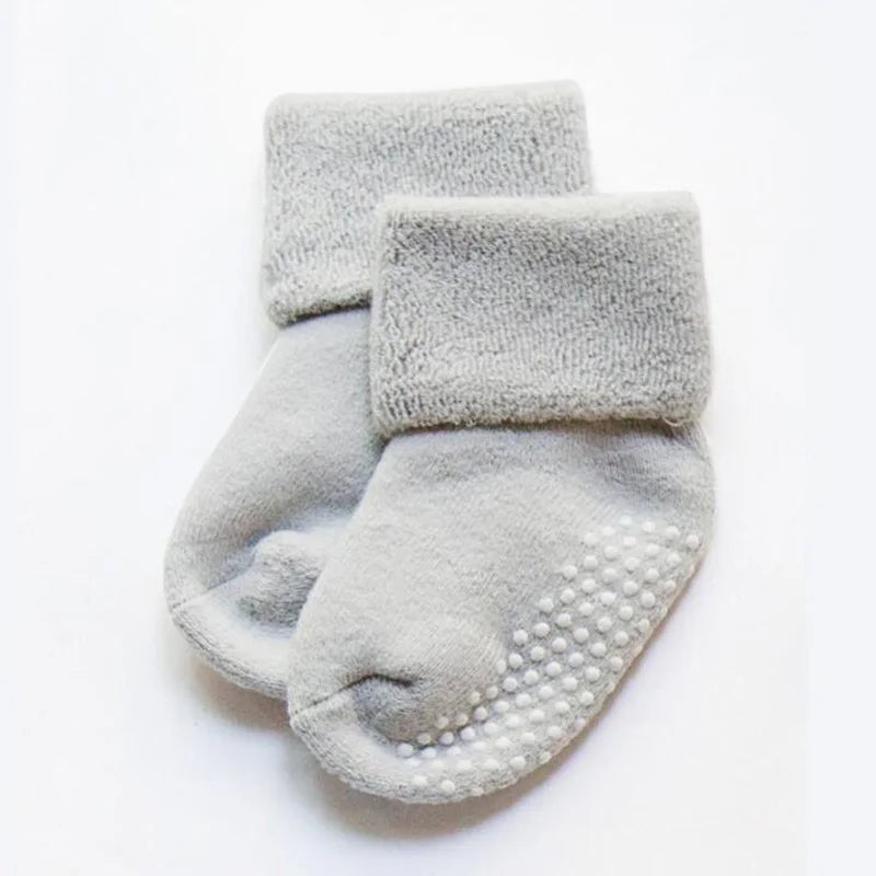 Light gray thick baby socks with white grippy dots on the sole