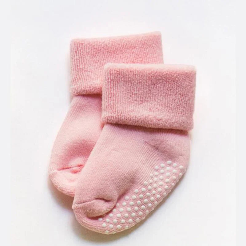 Pink thick baby socks with white grippy dots on the sole