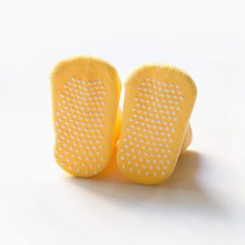 Yellow thick baby socks with white grippy dots on the soles