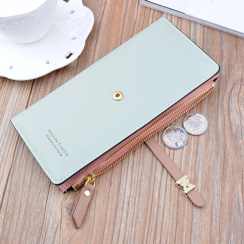 Long light blue wallet purse with gold button, zipper opening, and pink tassel pull.