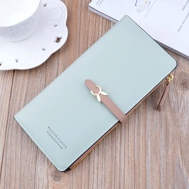 Long light blue leather wallet purse with gold zipper, bow strap, and snap closure.