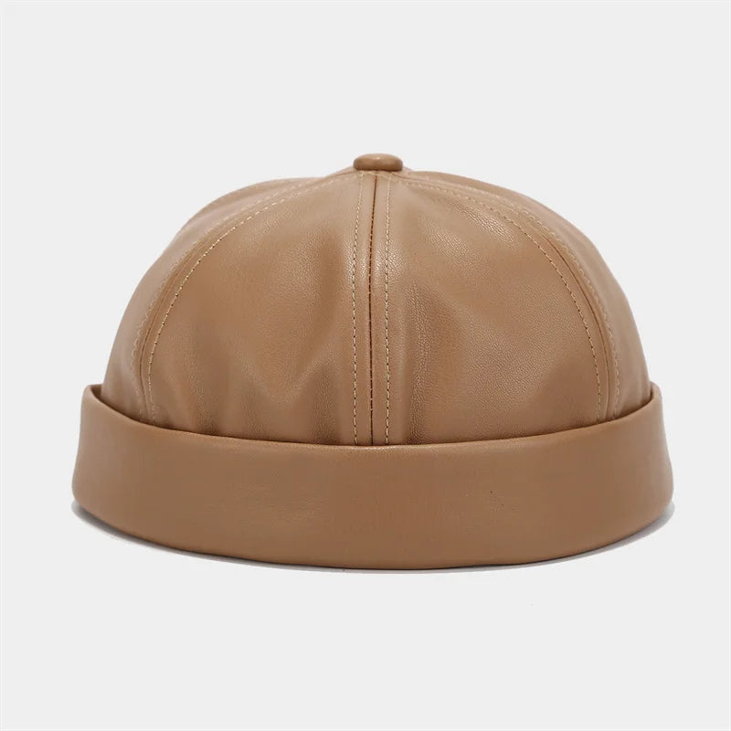 Light tan PU leather docker cap, domed crown with stitched vertical seam and top button.