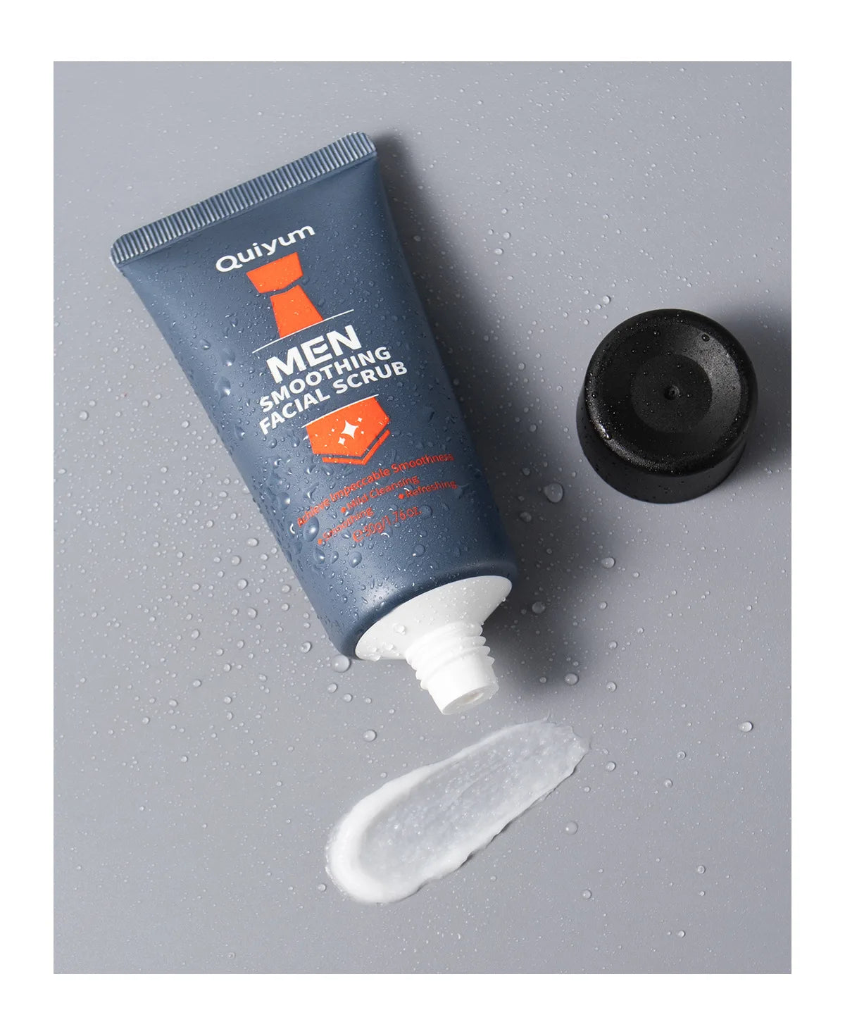 Men's facial scrub tube and creamy dollop on surface, with black cap beside it