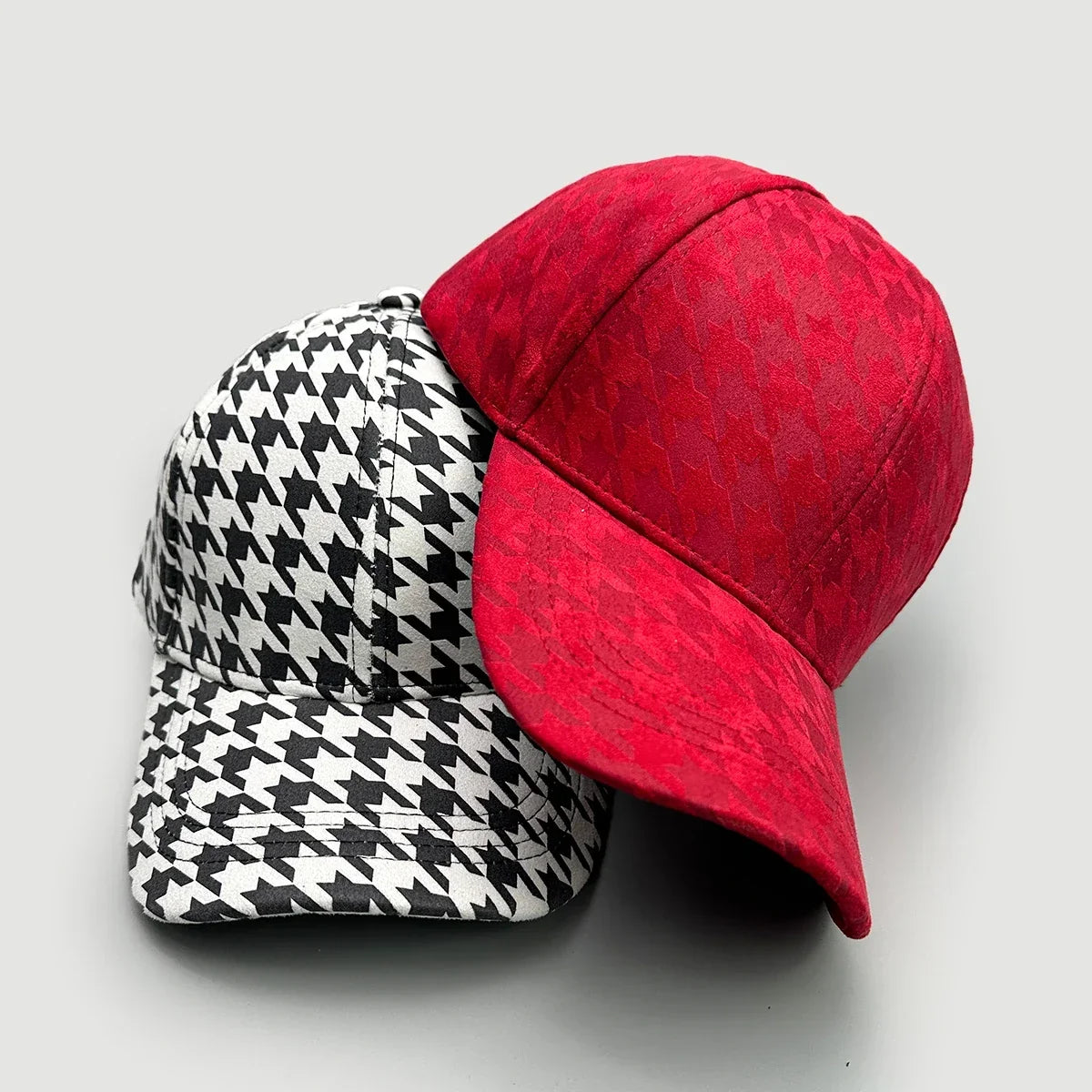 Two stylish baseball caps, one in red with a textured pattern and one in black and white houndstooth.