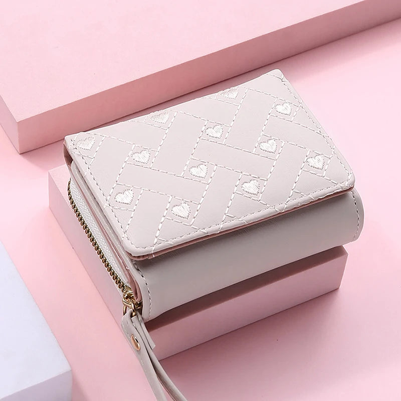 White small leather wallet with heart-stitched pattern, gold zipper, wrist strap