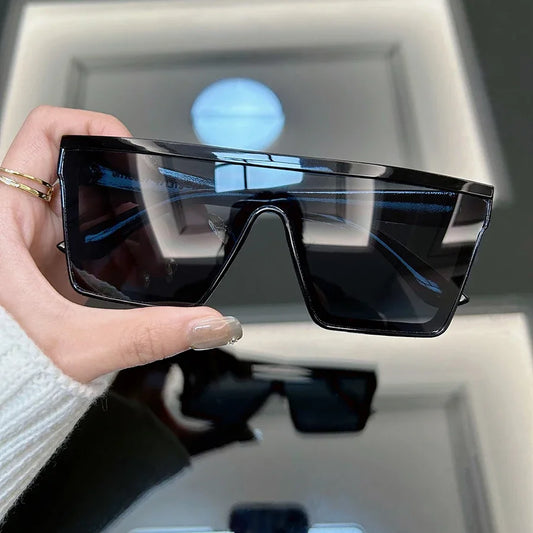 Unisex retro square sunglasses with black frame and dark lenses, held at an angle