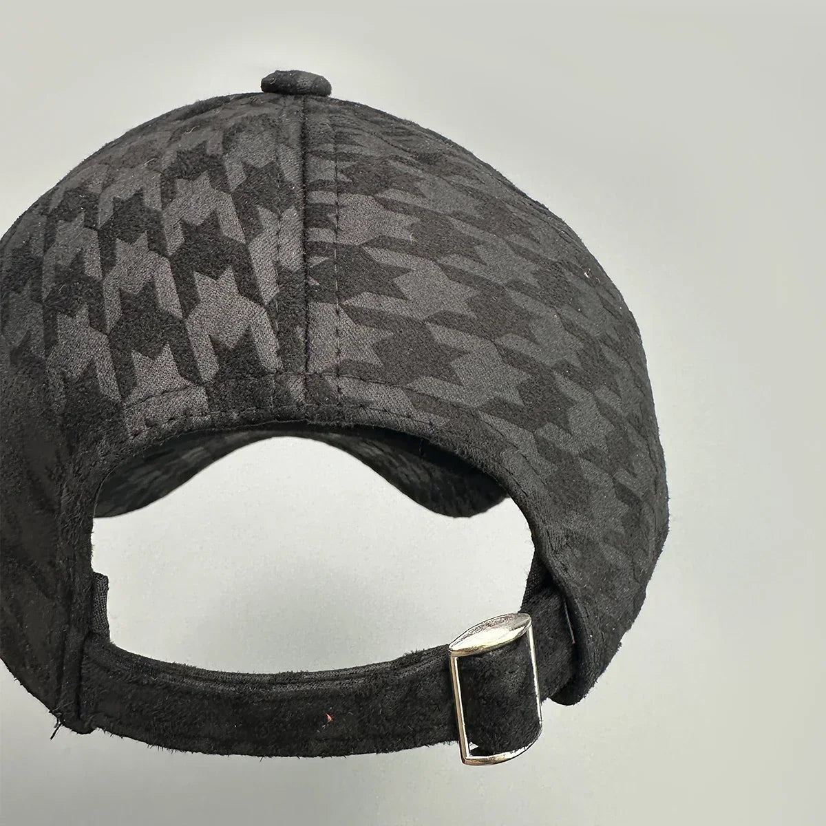 Back view of a black baseball cap with a subtle geometric pattern and adjustable strap.