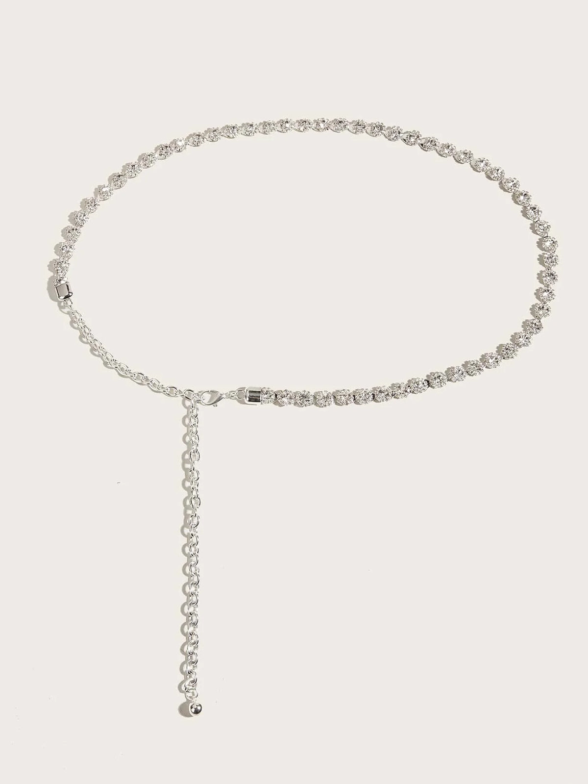 Silver rhinestone belt with long extender chain and metal clasp, flat lay