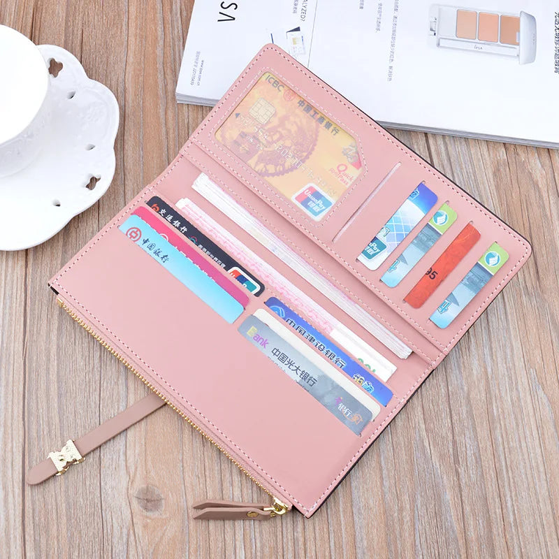 Long pink wallet purse opened to card slots and bill compartments with a bow strap.