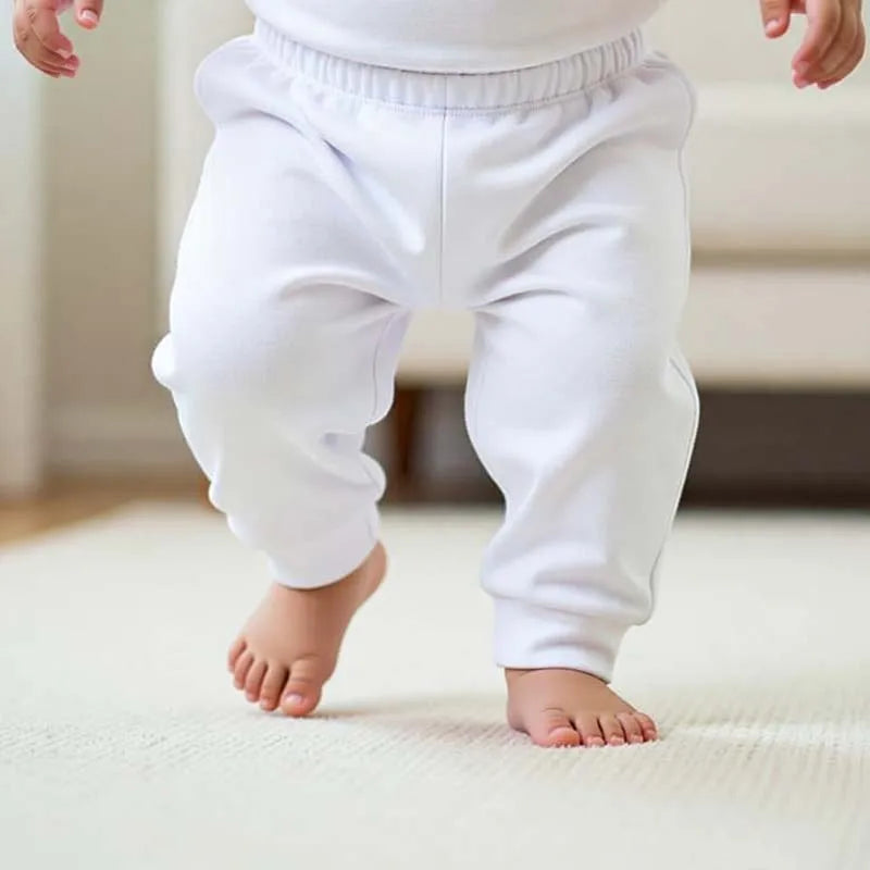White baby jogger pants on a standing child, cuffed ankle and elastic waist