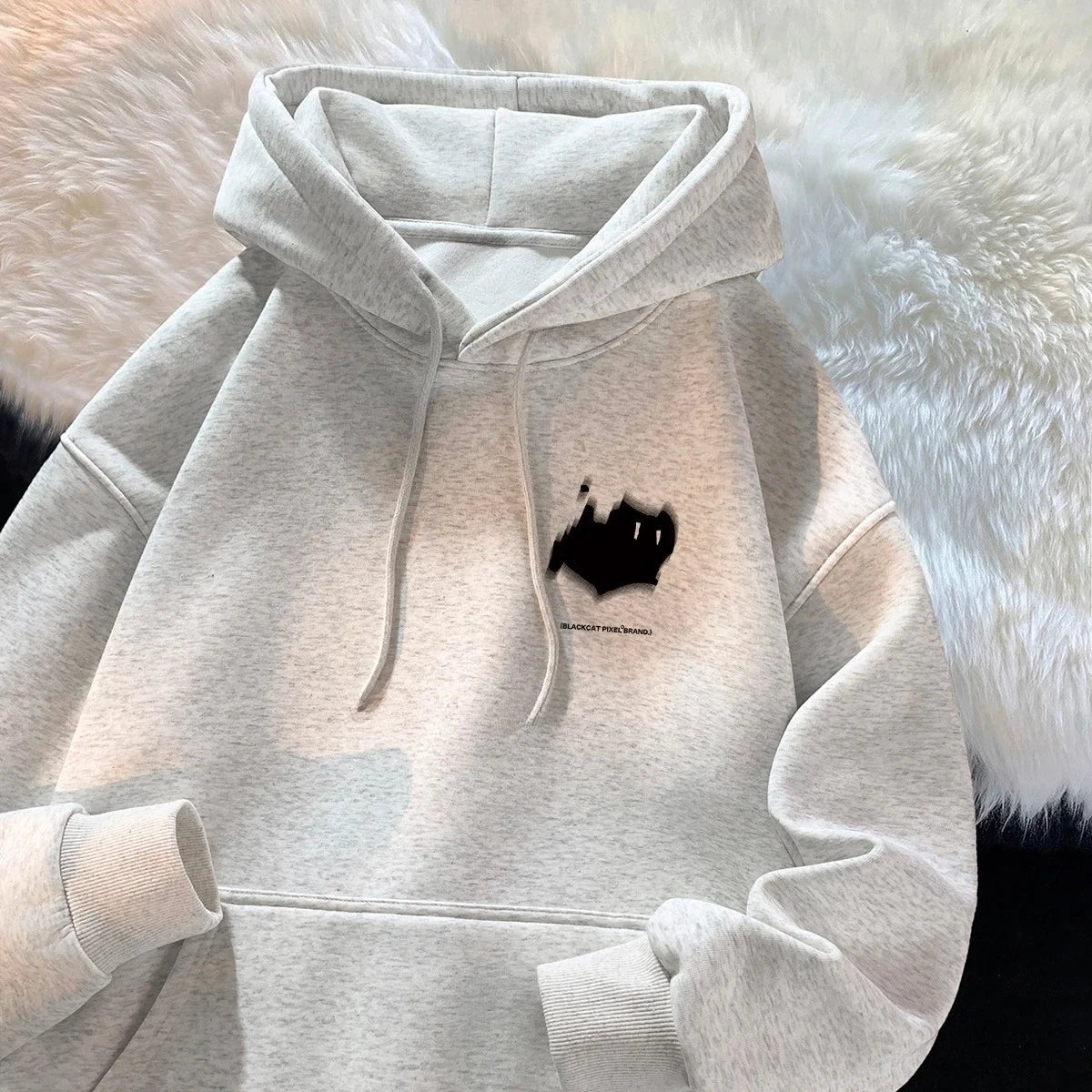 Light gray oversized women's hoodie with hood, drawstrings, front pocket, and chest graphic