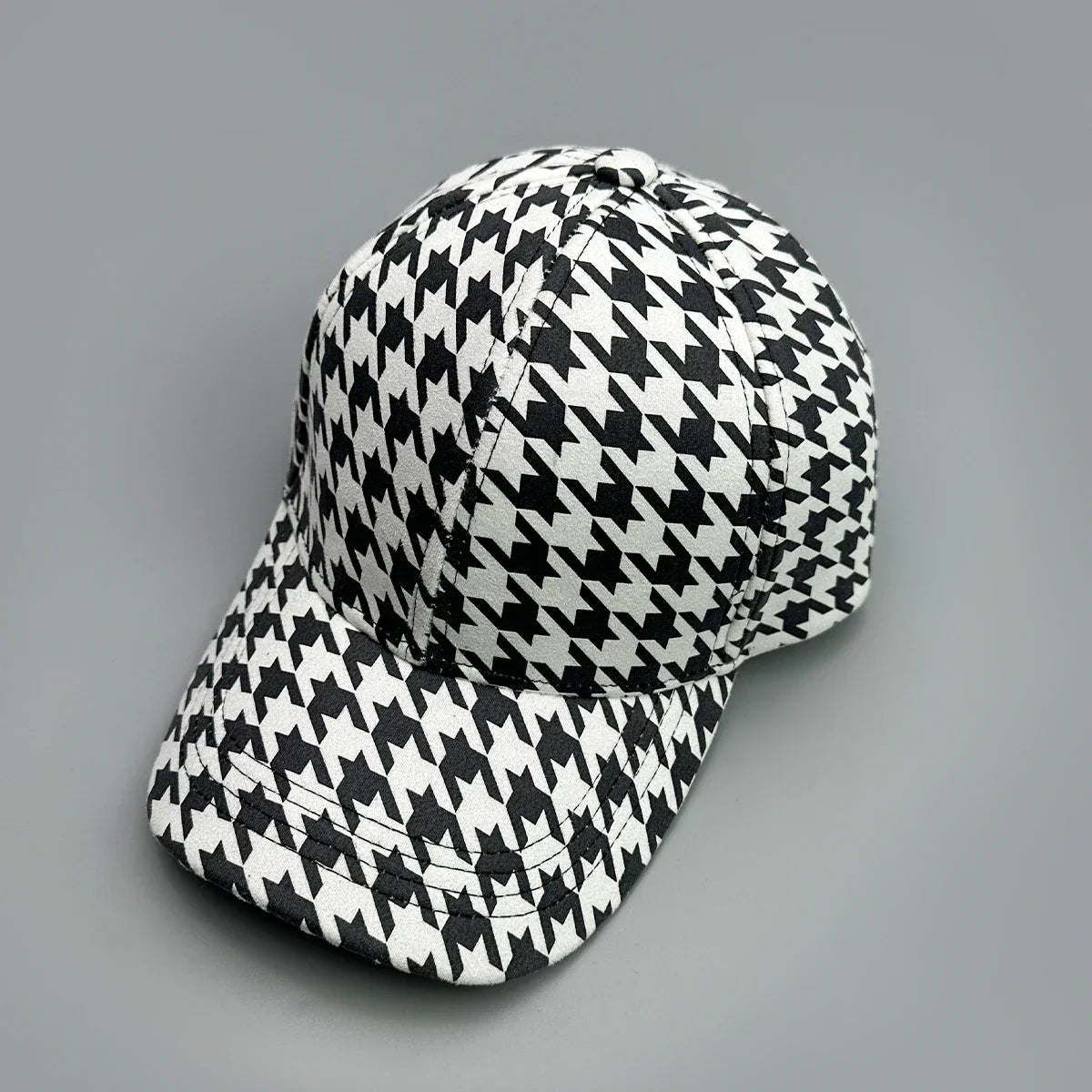 Black and white houndstooth pattern baseball cap on a grey background