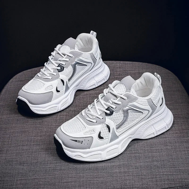 White chunky platform sneakers with dark logo accents and thick cushioned sole, angled