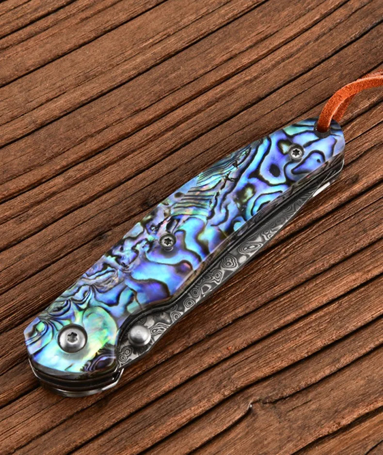 Damascus steel folding knife with iridescent blue-green handle, blade closed