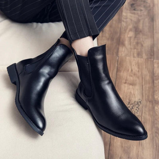 Pair of men's black leather Chelsea boots worn with pinstripe trousers.