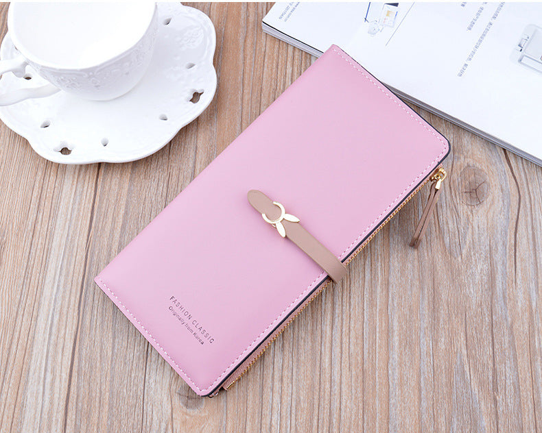Long pink wallet purse with bow strap, gold zipper, and smooth front panel.