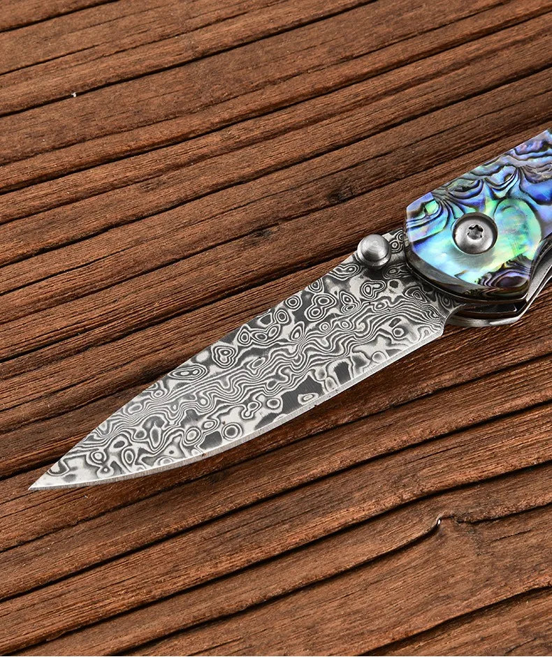 Damascus steel folding knife blade with swirled damascus pattern and iridescent blue handle