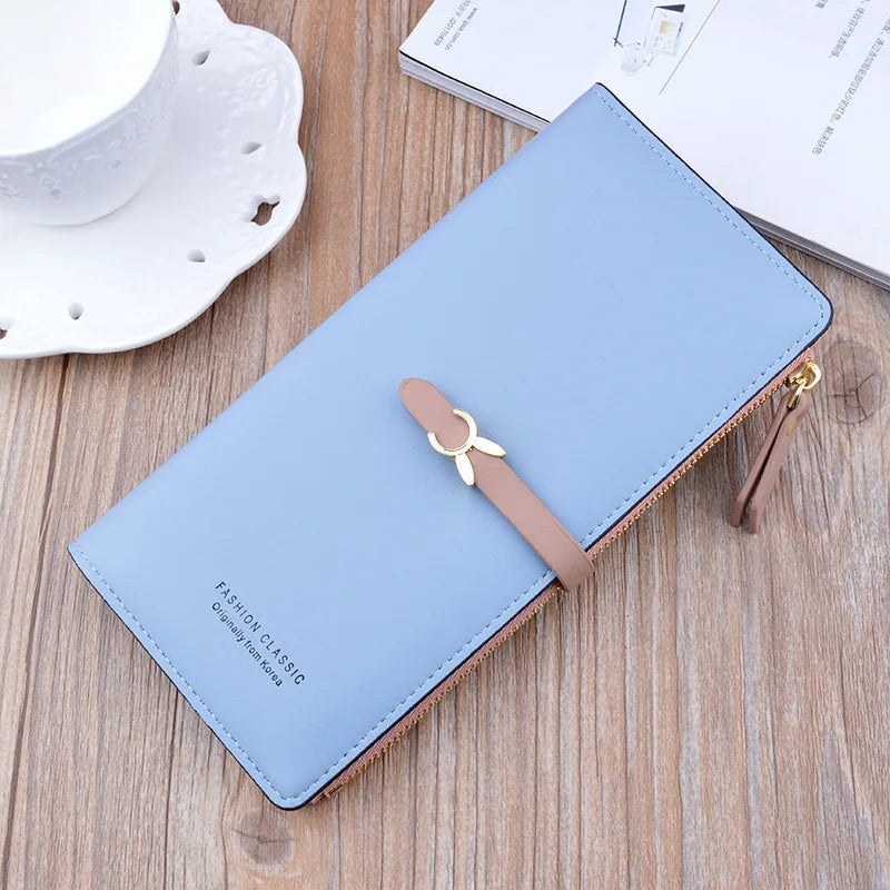 Long women's wallet purse, light blue with gold zipper and bow charm, front view