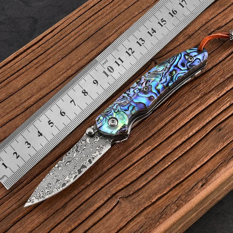 Damascus steel folding knife with iridescent blue handle and patterned damascus steel blade