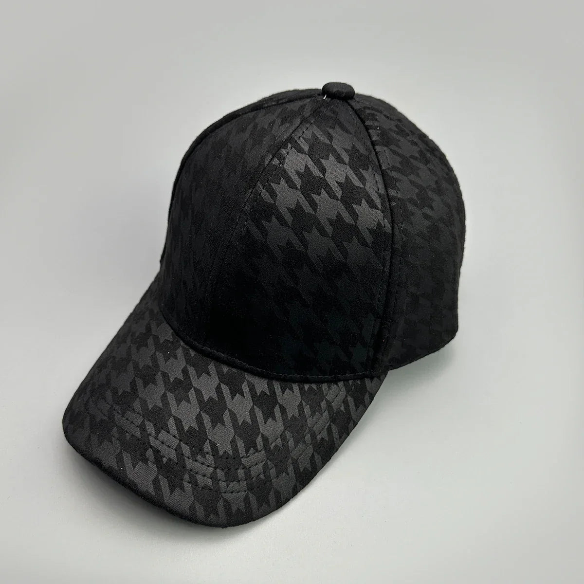 Black baseball cap with a subtle houndstooth pattern on a grey background